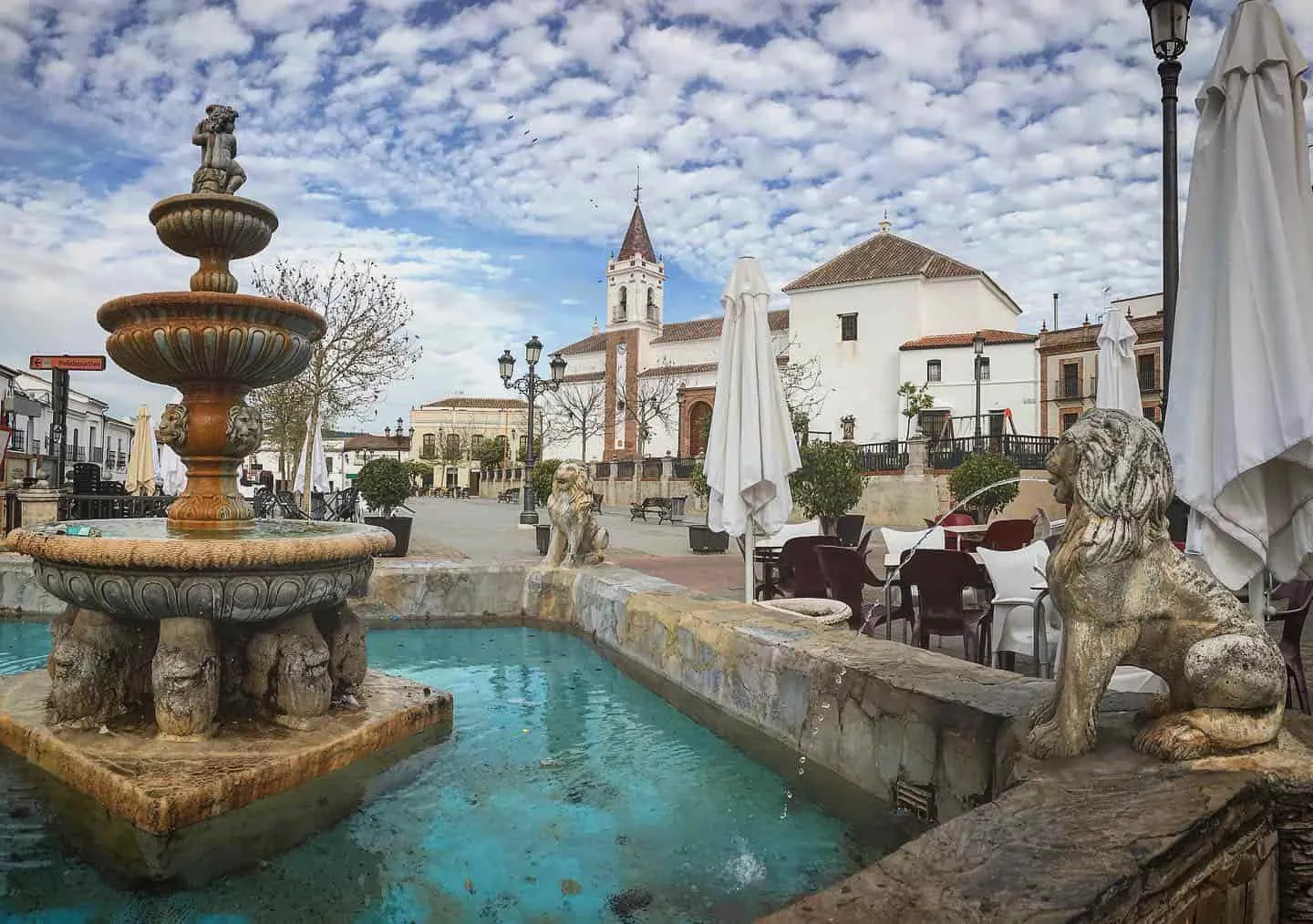 Vista de la plaza de Las Navas de la Concepción desde la fuente de los leones, con la iglesia y su campanario al fondo.