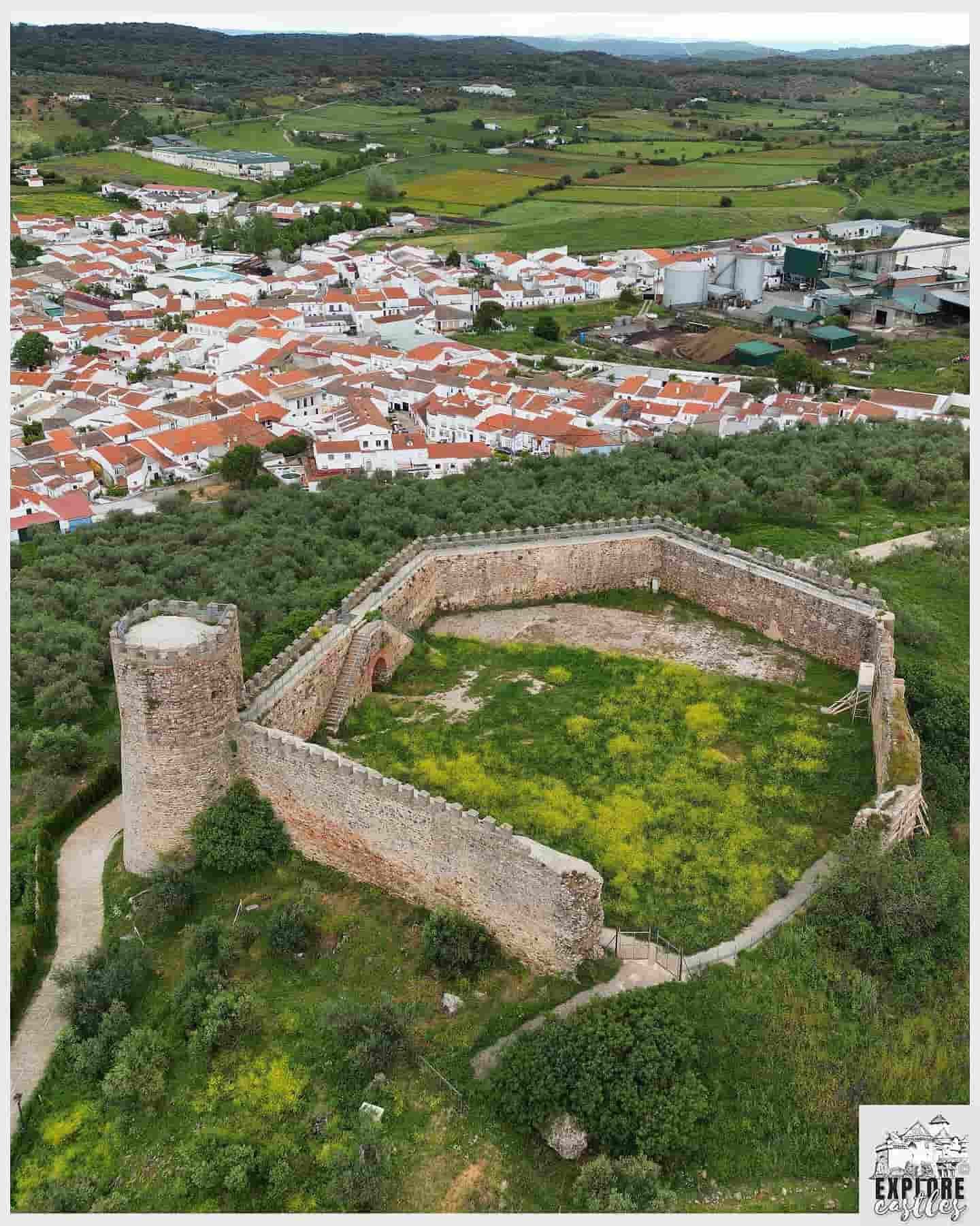 Imagen aérea del castillo en ruinas de Alanís con el pueblo y sus casas blancas de fondo.