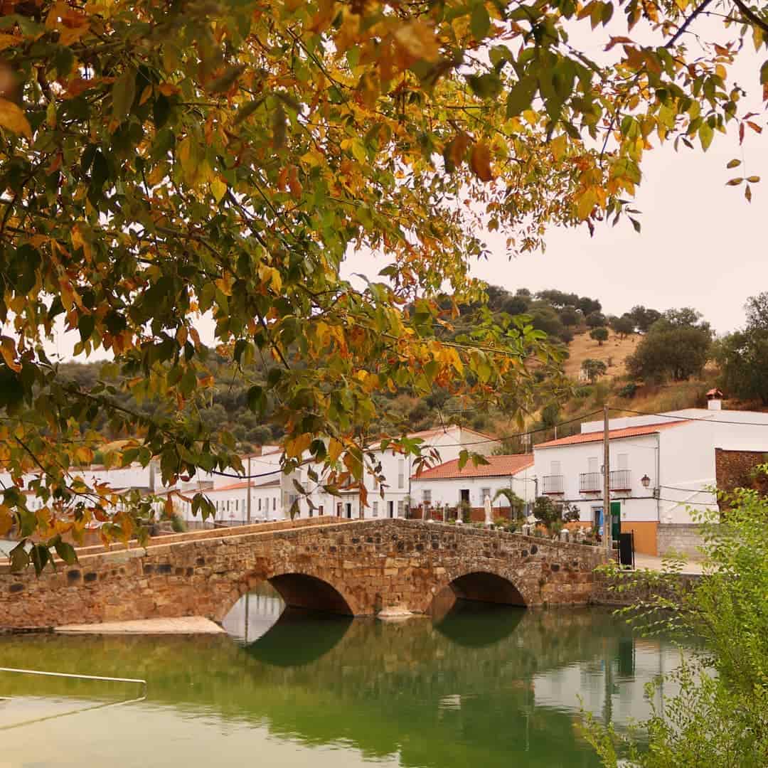Vista del puente de San Nicolás del Puerto sobre la playa artificial, con las calles del pueblo al fondo en un día nublado.